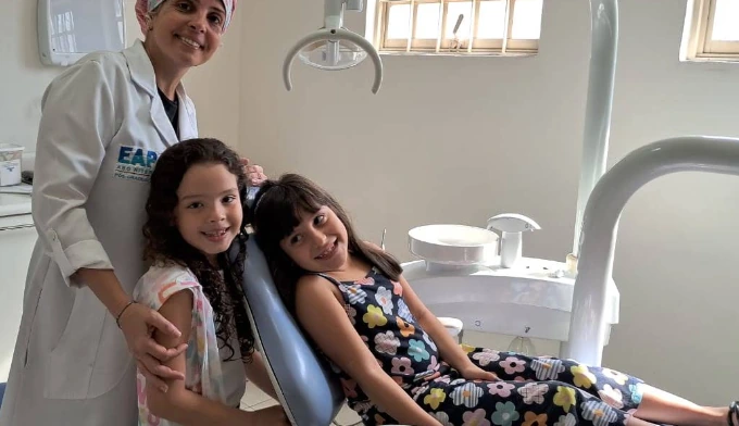 Dra. Elisa com duas crianças no consultório odontológico